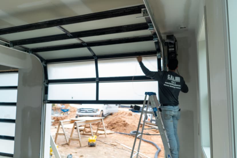 Worker installing a garage door opener in a modern home under construction.