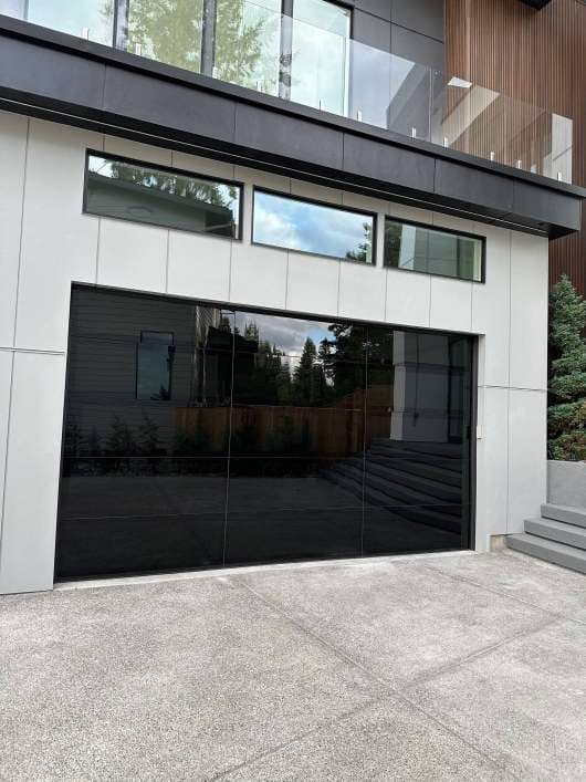 Modern home exterior with sleek glass garage door and minimalist design elements.