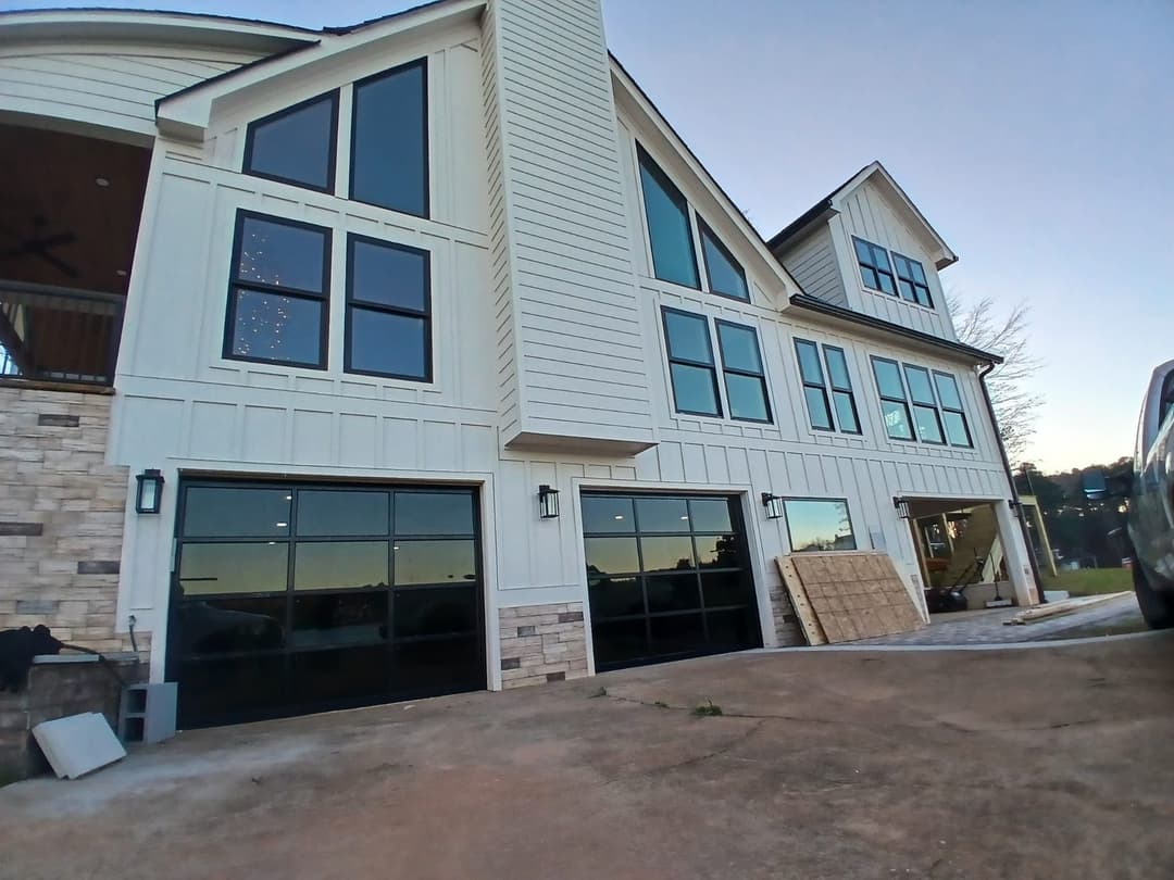 Modern white house with large windows and stone accents, featuring a two-car garage.