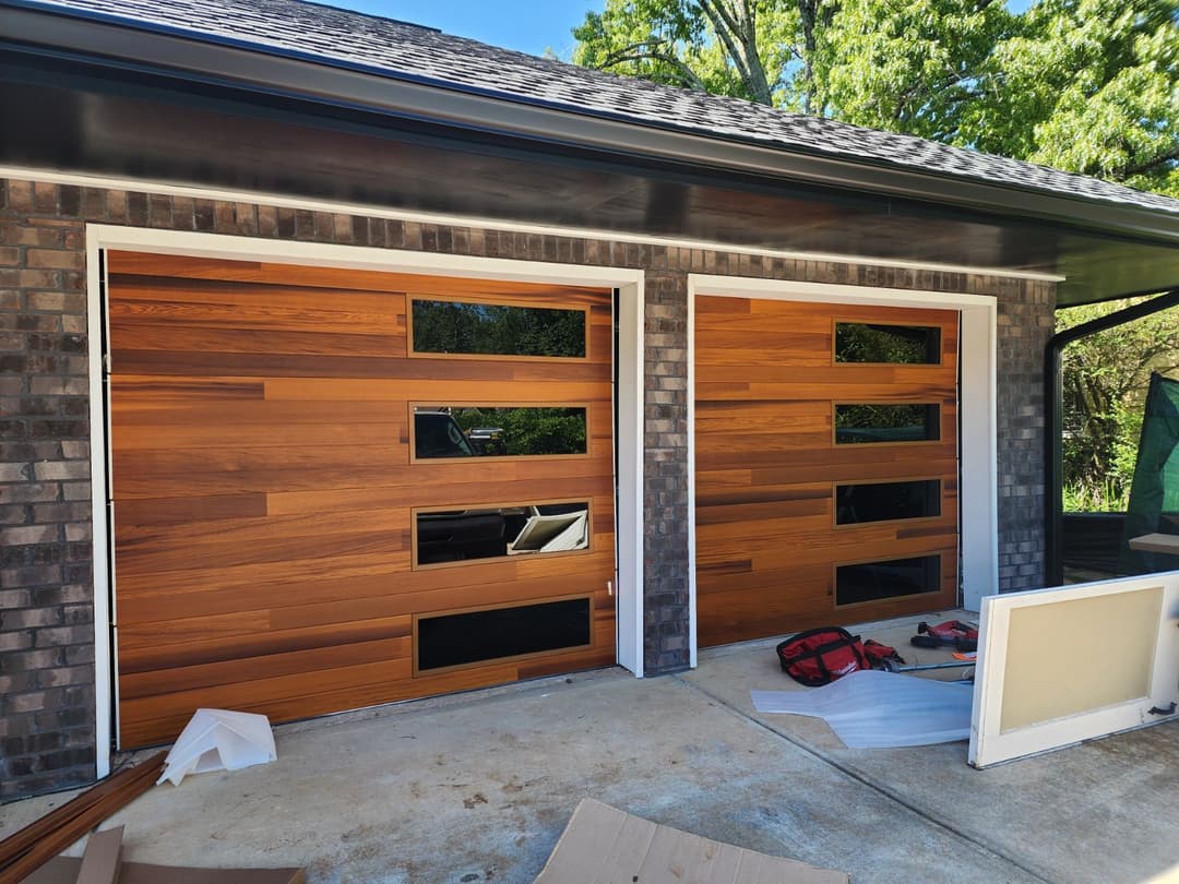 Modern wooden garage doors with horizontal slats and glass panels, framed in white.