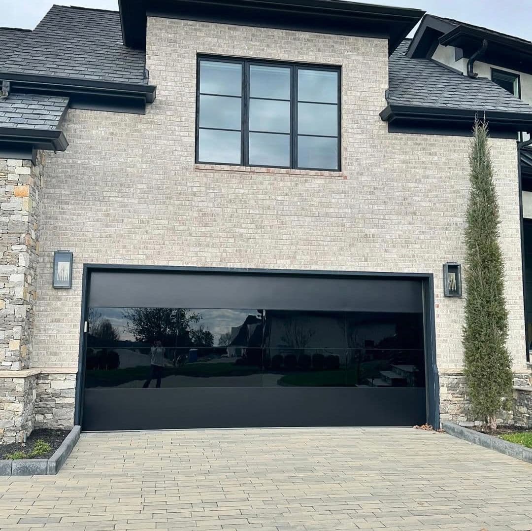 Contemporary home exterior with large black garage door and stone accents.