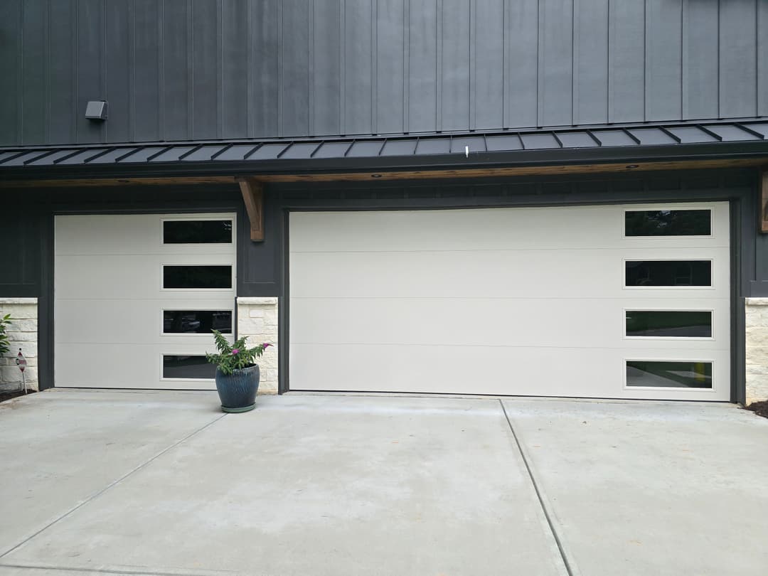 Modern house with two stylish garage doors featuring windows, set against a sleek exterior.