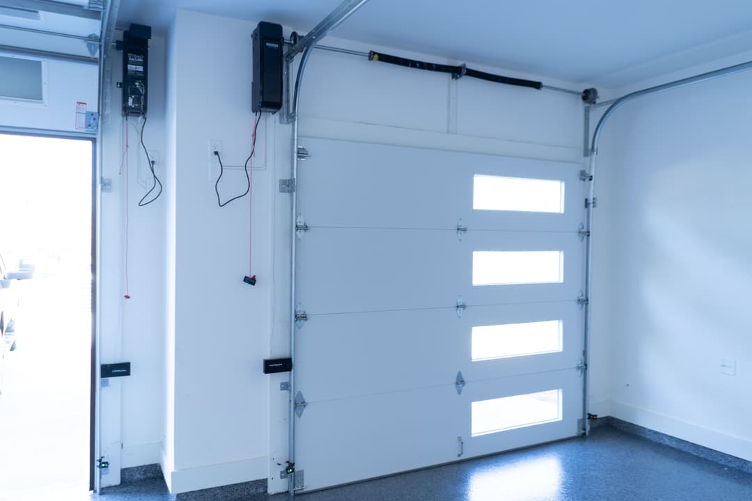 Modern garage interior featuring a white sectional door with windows and wall-mounted controls.