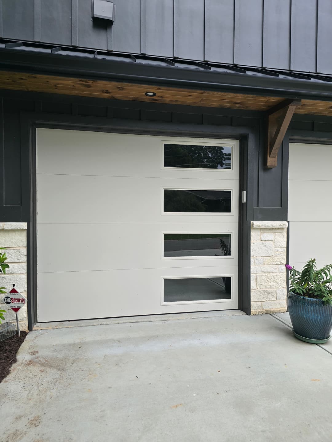 Modern garage door with horizontal windows, gray design, and stylish stone accents.