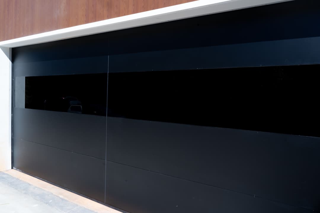 Modern black garage door with sleek design and large glass panels for natural light.