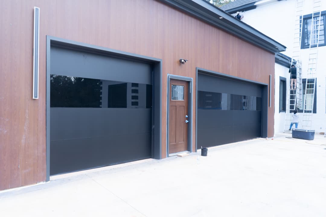 Modern home with dual black garage doors and a wooden exterior detail.