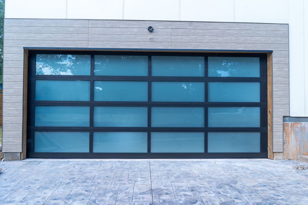 Modern garage door with frosted glass panels and sleek black frame on a contemporary building.